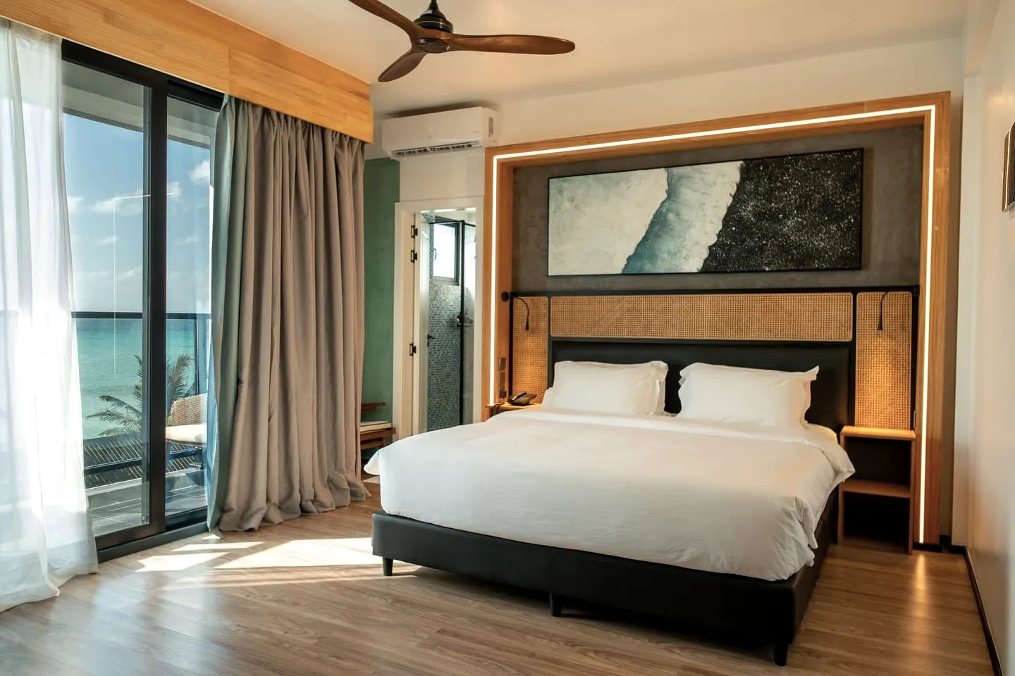 A bedroom opening onto a balcony, with the sea beyond the doors