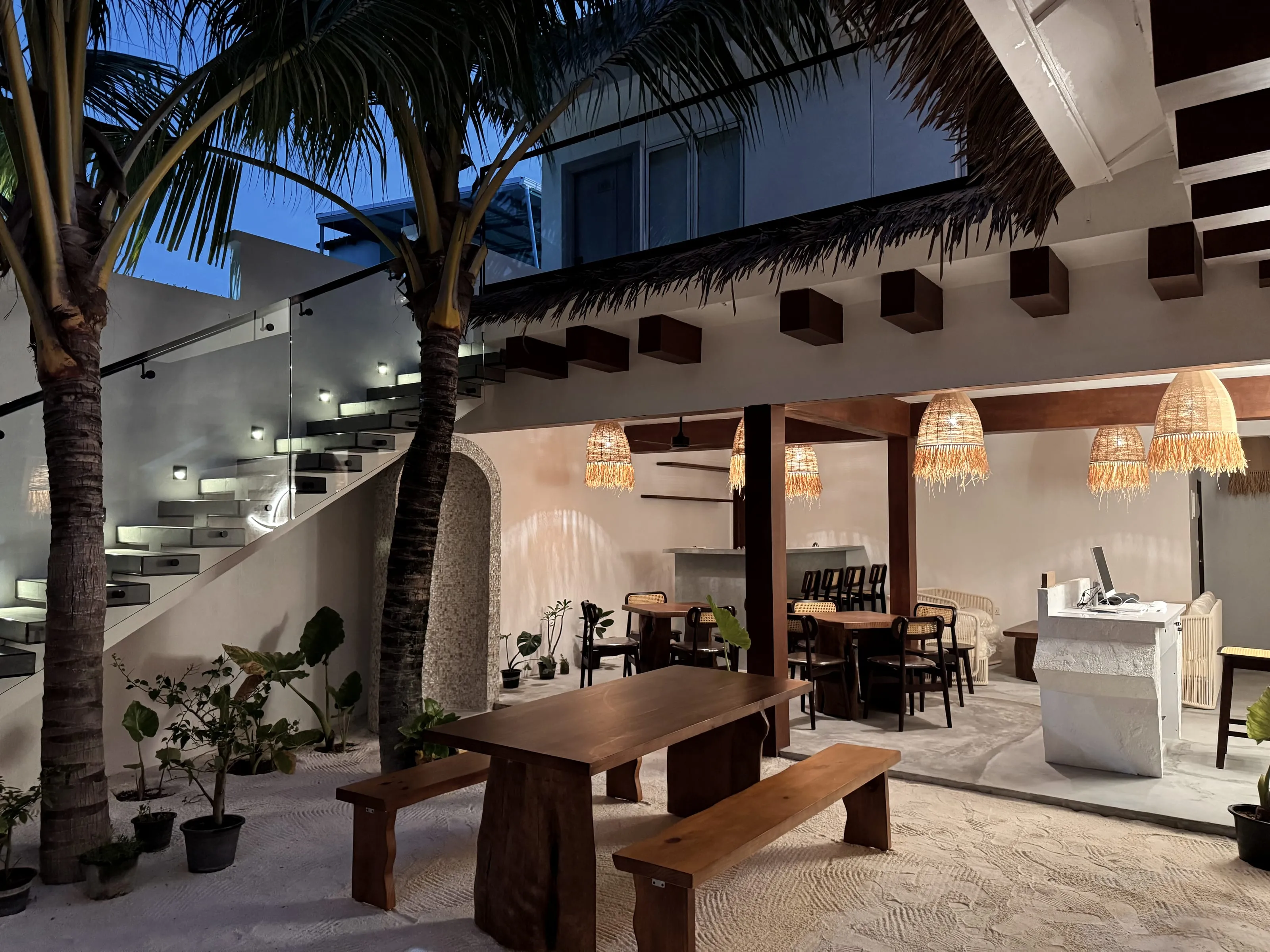 A courtyard dining room open to the palms, under a thatched roof