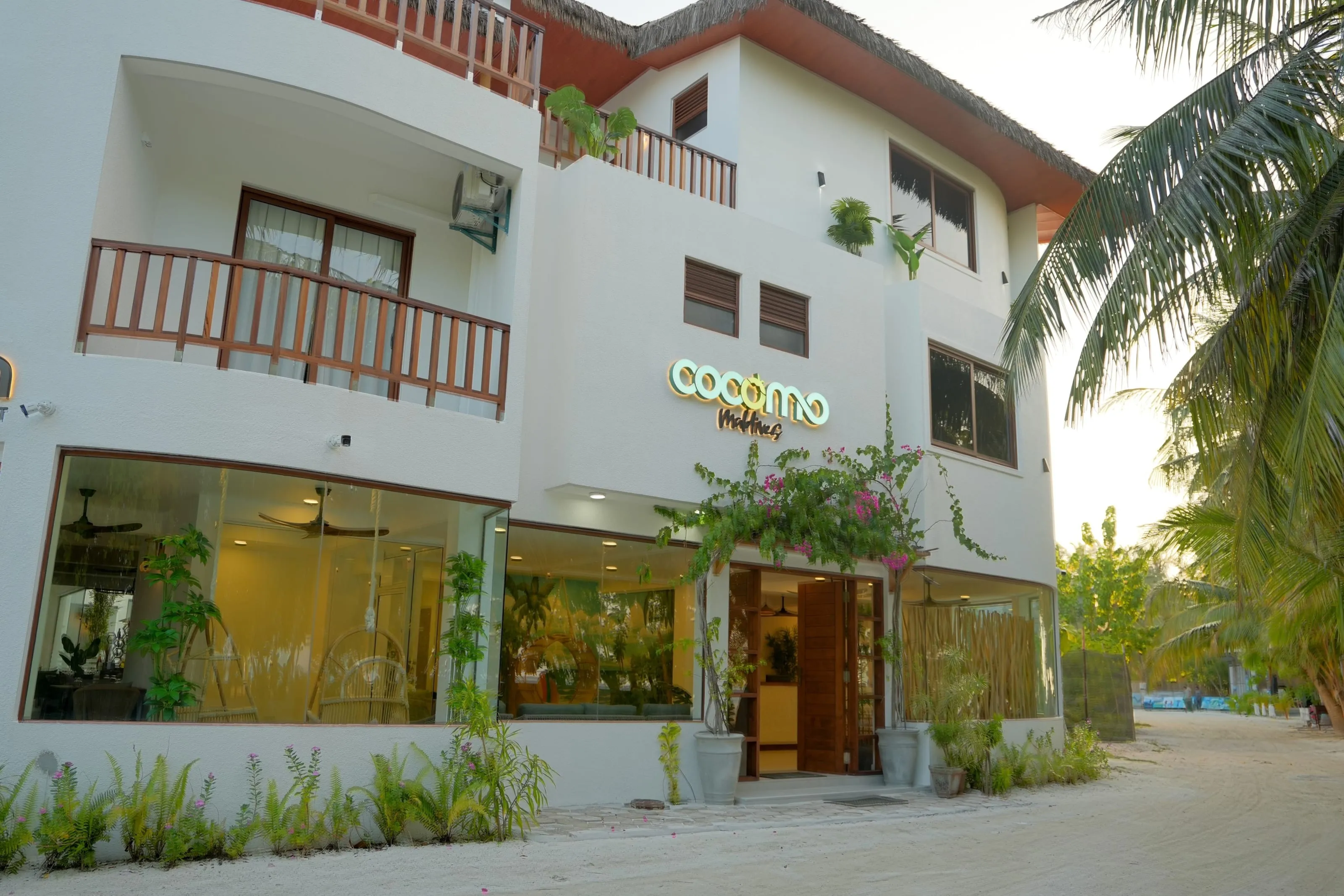 A white facade with the Cocomo sign, bougainvillea over the entrance